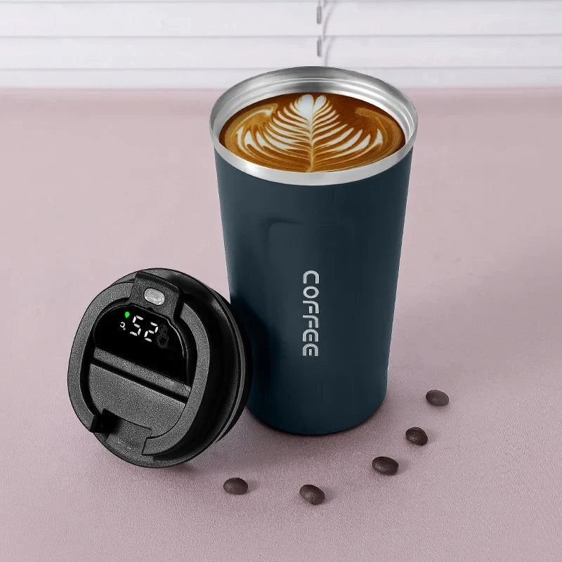 Insulated coffee travel mug with digital lid and latte art, coffee beans nearby